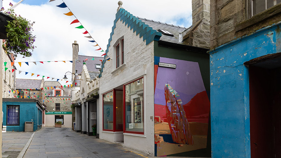 Gebouwen van baksteen in Lerwick, kleurrijke streetart en op veel plaatsen verlaten nederzettingen.