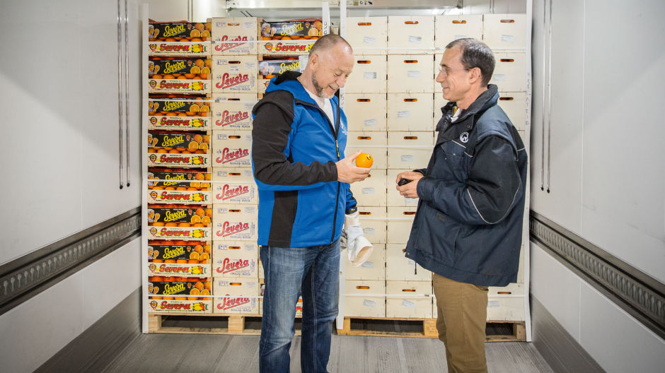 Georg Hegelmann carga naranjas en el centro logístico de Perpiñán mientra charla con sus clientes.